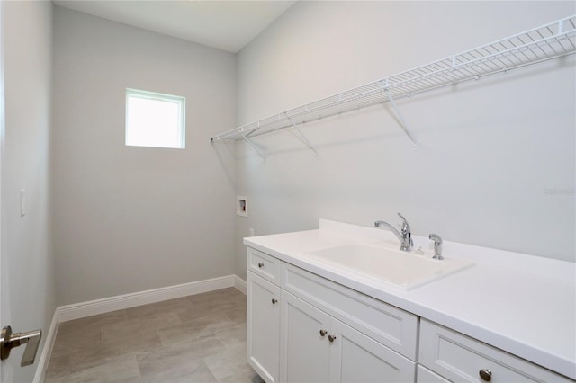 clothes washing area with cabinet space, baseboards, washer hookup, and a sink