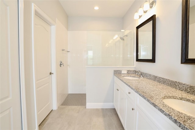 bathroom featuring double vanity, walk in shower, a sink, and tile patterned floors