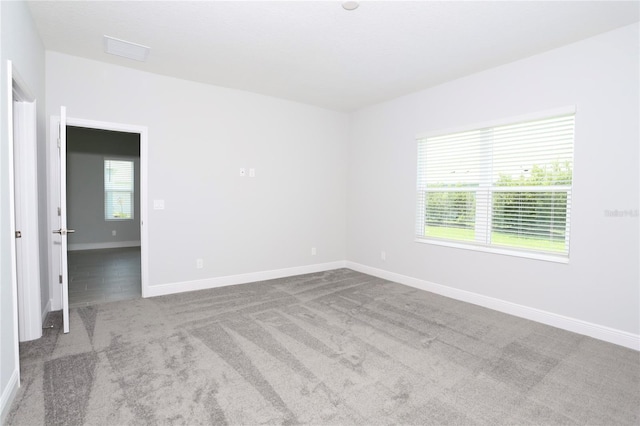 carpeted empty room featuring visible vents and baseboards