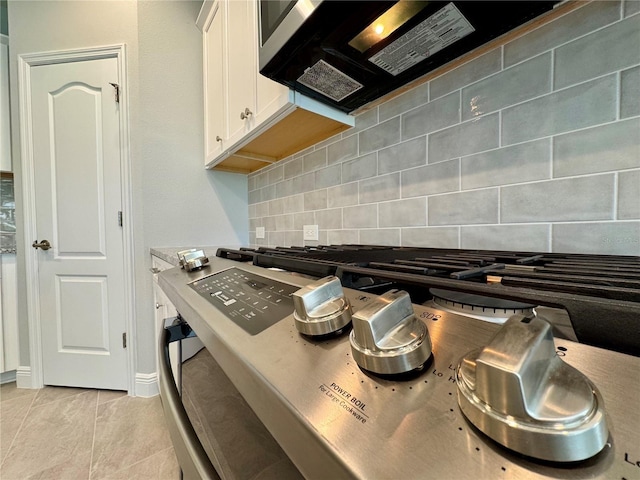 14552 Skipping Stone Loop, Parrish, FL 34219 - kitchen with white cabinetry, black microwave, stovetop, and tasteful backsplash