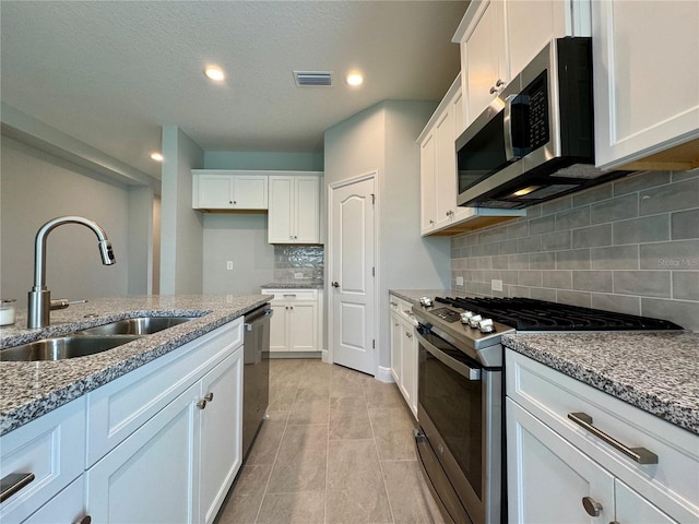 14552 Skipping Stone Loop, Parrish, FL 34219 - kitchen with stainless steel appliances, stone counters, a sink, and white cabinetry
