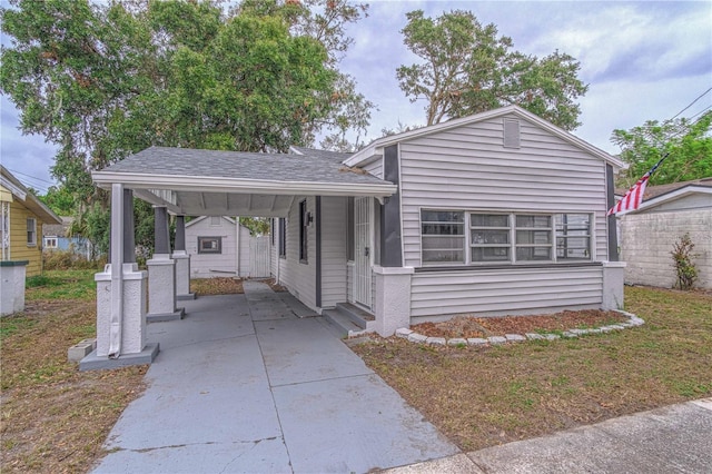 view of front of home with a carport, a shingled roof, and driveway