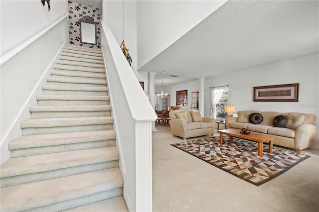 stairway featuring carpet floors, a textured ceiling, an inviting chandelier, and ornate columns