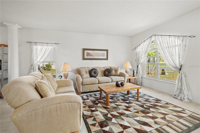 carpeted living area featuring decorative columns, baseboards, and a textured ceiling