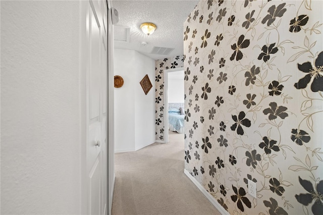 corridor with visible vents, a textured ceiling, and carpet flooring