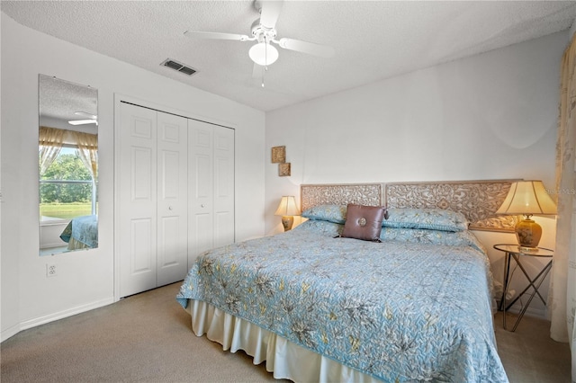 bedroom with carpet, visible vents, ceiling fan, a closet, and a textured ceiling