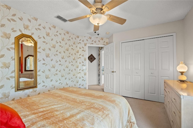 bedroom featuring wallpapered walls, a textured ceiling, visible vents, and light carpet