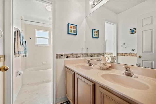 full bathroom with double vanity, shower / washtub combination, a textured ceiling, and a sink