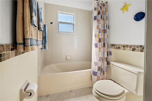 full bath featuring toilet, tile walls, and shower / bath combination with curtain