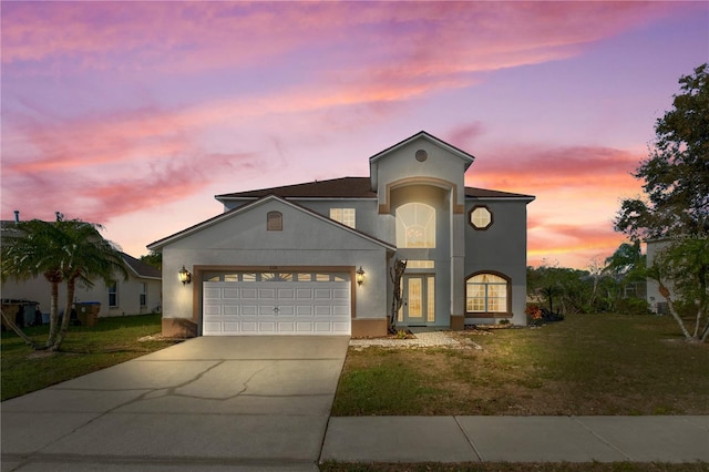 view of front facade with a front yard, concrete driveway, a garage, and stucco siding