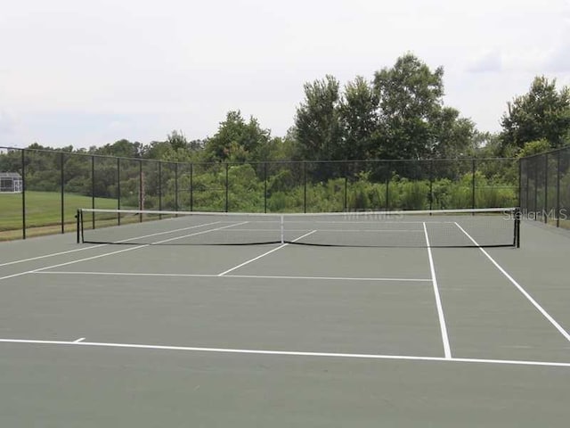 view of tennis court featuring community basketball court and fence