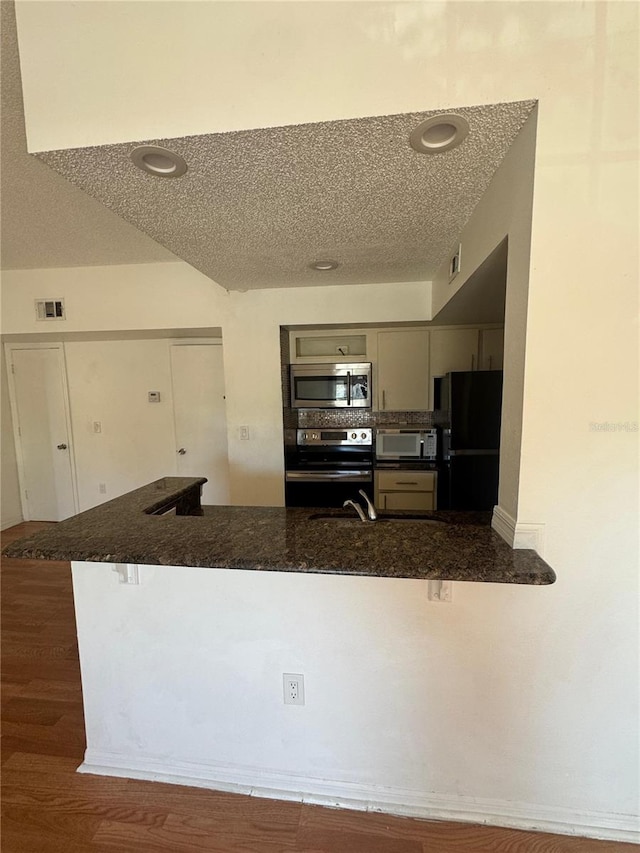 445 Fountainhead Cir Unit 264, Kissimmee, FL 34741 - kitchen featuring gray cabinets, appliances with stainless steel finishes, a peninsula, wood finished floors, and a textured ceiling