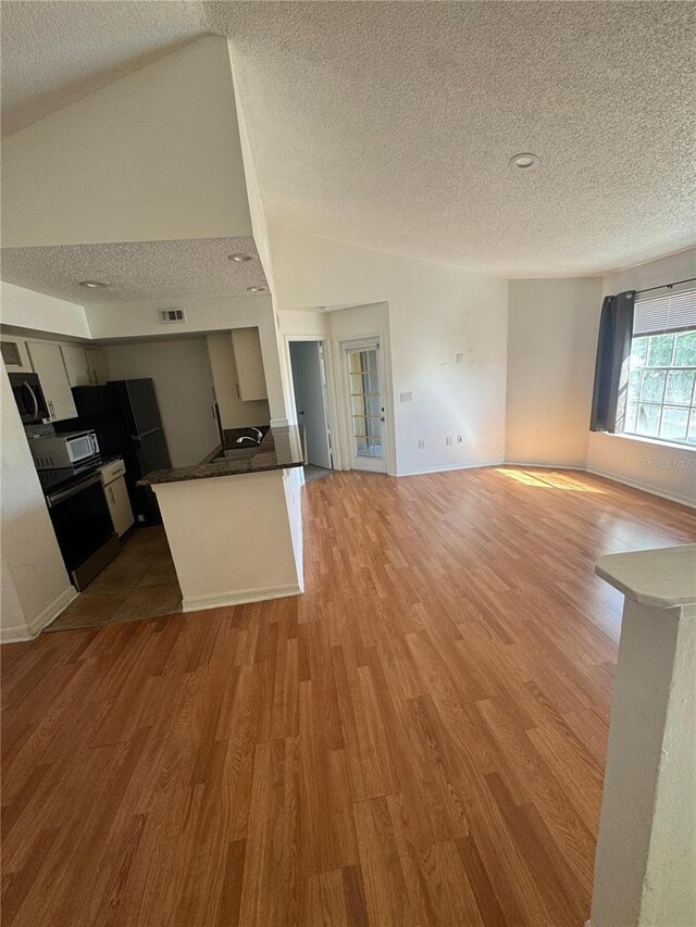 445 Fountainhead Cir Unit 264, Kissimmee, FL 34741 - kitchen with lofted ceiling, freestanding refrigerator, visible vents, and light wood finished floors