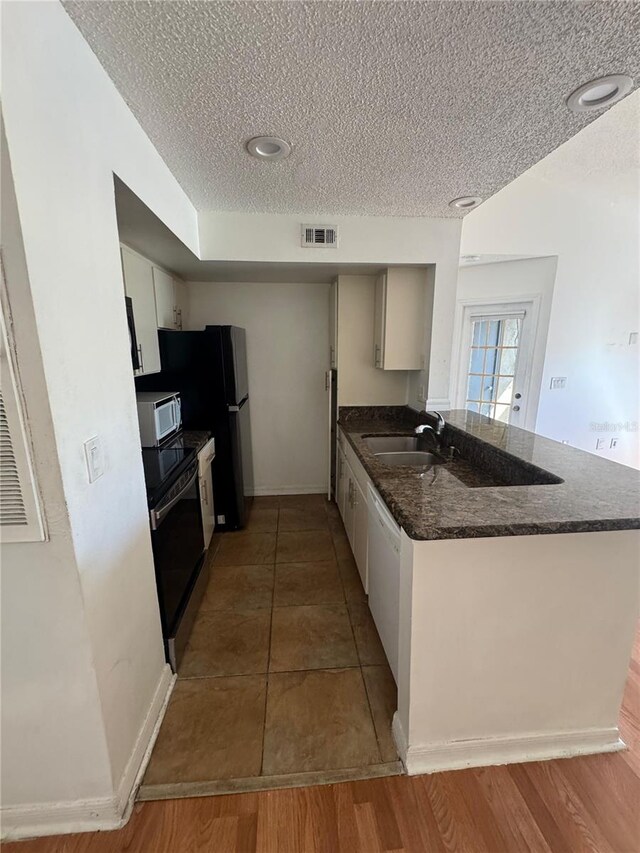 445 Fountainhead Cir Unit 264, Kissimmee, FL 34741 - kitchen with visible vents, a sink, a textured ceiling, white appliances, and a peninsula