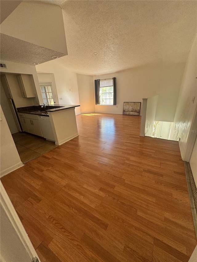 445 Fountainhead Cir Unit 264, Kissimmee, FL 34741 - kitchen with a textured ceiling, dark countertops, open floor plan, dark wood finished floors, and a peninsula