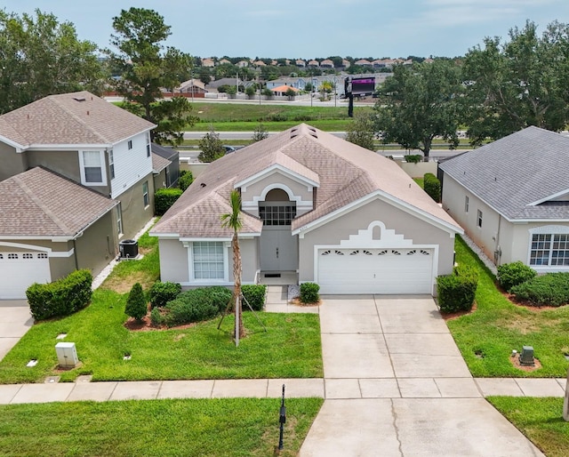8204 Fan Palm Way, Kissimmee, FL 34747 - view of front facade featuring a garage, concrete driveway, central AC, stucco siding, and a residential view
