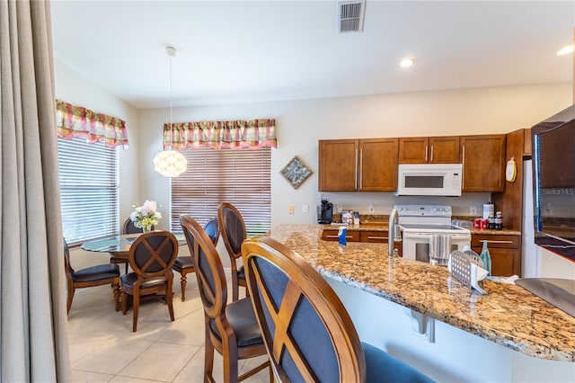 8204 Fan Palm Way, Kissimmee, FL 34747 - kitchen with white appliances, a kitchen bar, brown cabinetry, light tile patterned flooring, and pendant lighting