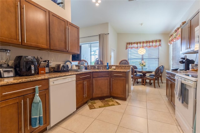 8204 Fan Palm Way, Kissimmee, FL 34747 - kitchen with white appliances, brown cabinetry, a peninsula, light tile patterned floors, and lofted ceiling
