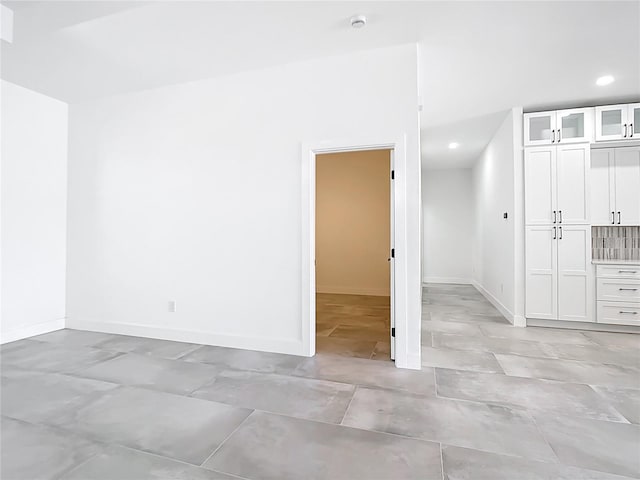 spare room featuring recessed lighting and baseboards