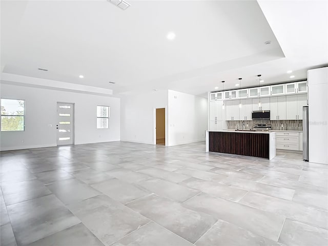 unfurnished living room with visible vents, recessed lighting, and a tray ceiling