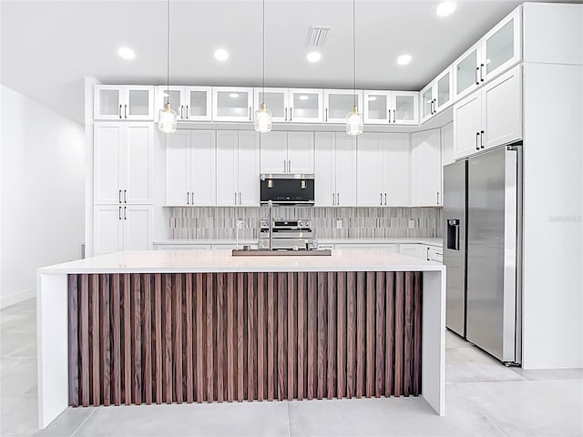 kitchen featuring decorative backsplash, a center island with sink, appliances with stainless steel finishes, and light countertops