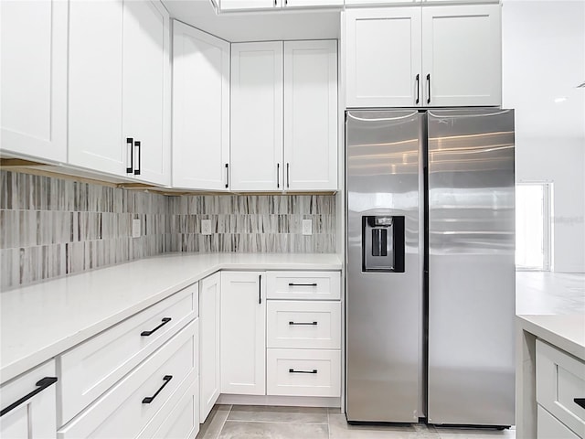 kitchen with white cabinetry, backsplash, stainless steel refrigerator with ice dispenser, and light countertops