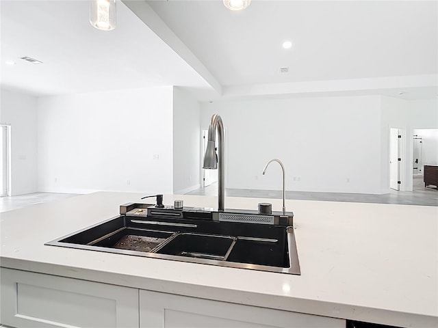 kitchen featuring visible vents, open floor plan, recessed lighting, white cabinetry, and a sink