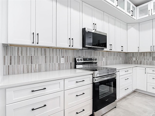 kitchen with light countertops, glass insert cabinets, appliances with stainless steel finishes, white cabinetry, and backsplash