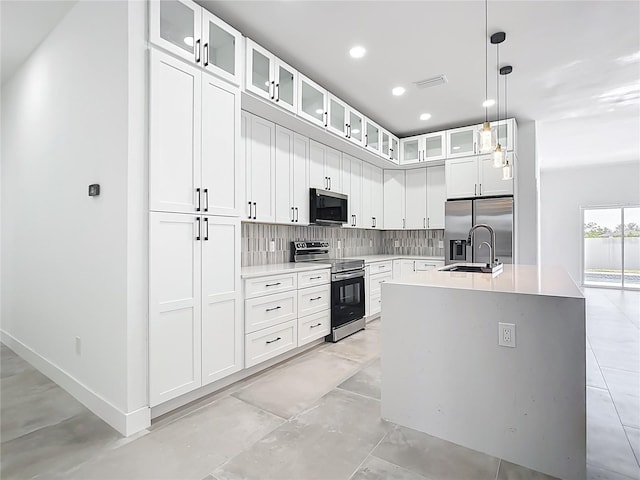 kitchen featuring tasteful backsplash, visible vents, a center island with sink, light countertops, and appliances with stainless steel finishes