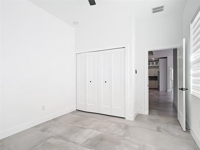 unfurnished bedroom with visible vents, baseboards, and a towering ceiling