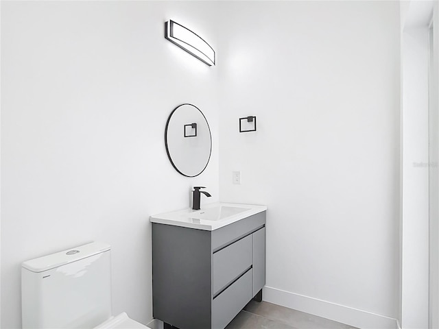 half bath with vanity, toilet, and baseboards