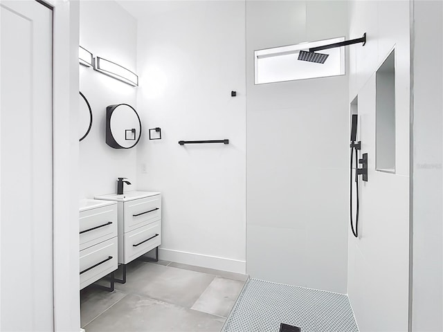 full bathroom featuring tiled shower, vanity, and baseboards