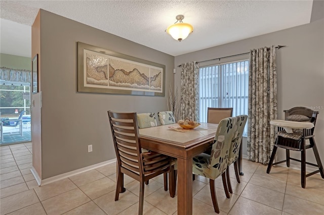 dining room featuring a textured ceiling, light tile patterned floors, and baseboards