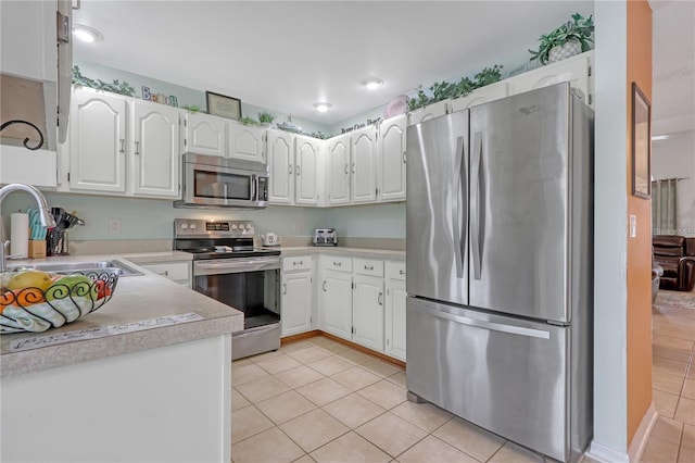 kitchen featuring light tile patterned floors, white cabinetry, appliances with stainless steel finishes, and a sink