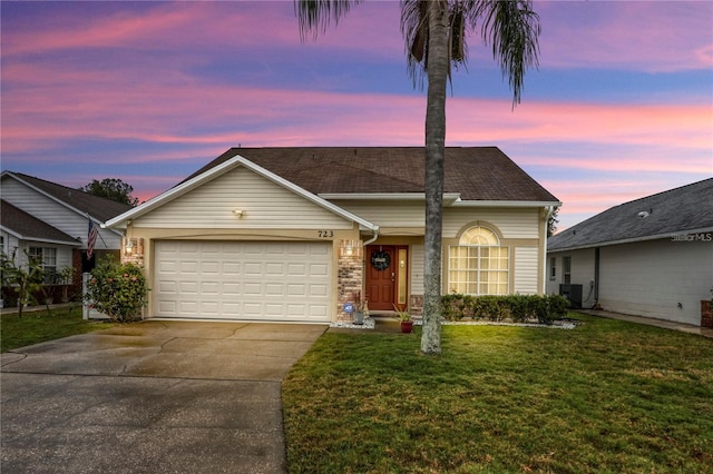 ranch-style home with an attached garage, cooling unit, a shingled roof, a yard, and concrete driveway