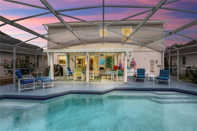 outdoor pool featuring glass enclosure and a patio