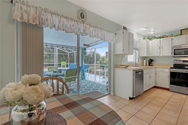 kitchen featuring a sunroom, stainless steel appliances, light countertops, a sink, and light tile patterned flooring