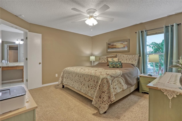 bedroom with a textured ceiling, ceiling fan, ensuite bathroom, and light colored carpet