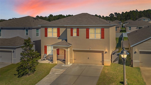 view of front of property with concrete driveway, a yard, an attached garage, and stucco siding