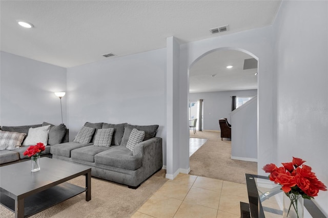 living area with arched walkways, visible vents, baseboards, and light tile patterned floors