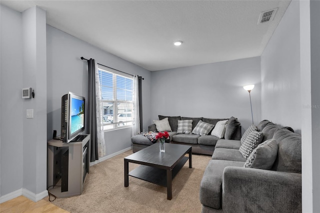 living room with light carpet, visible vents, and baseboards