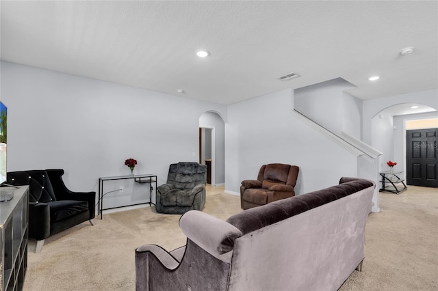 living area featuring visible vents, recessed lighting, arched walkways, a textured ceiling, and light carpet