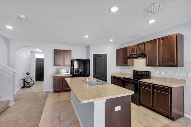 kitchen featuring visible vents, black appliances, under cabinet range hood, a sink, and arched walkways