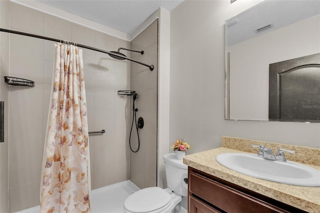 full bathroom featuring tiled shower, toilet, vanity, and a textured ceiling