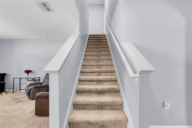 staircase featuring visible vents, a textured ceiling, and carpet