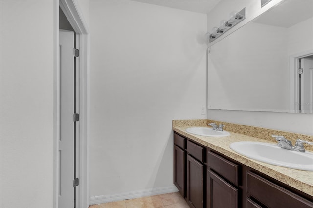 bathroom featuring a sink, baseboards, double vanity, and tile patterned flooring