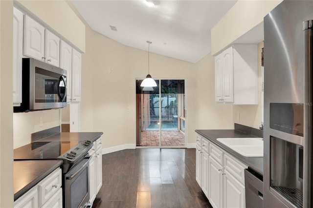 kitchen featuring appliances with stainless steel finishes, dark countertops, dark wood-type flooring, and a sink