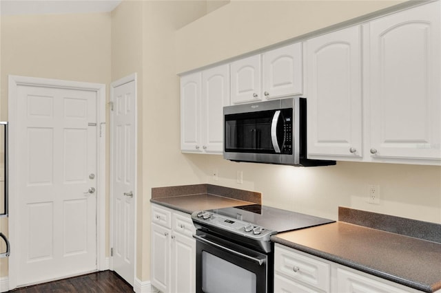 kitchen with electric range, stainless steel microwave, dark countertops, and white cabinetry