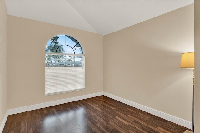 spare room with lofted ceiling, dark wood-style flooring, and baseboards