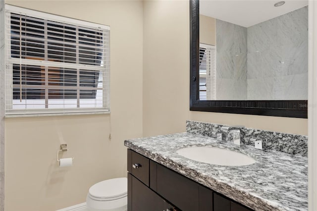 bathroom featuring toilet, baseboards, and vanity